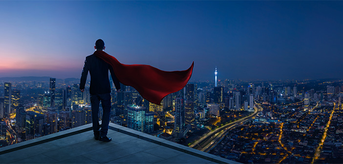 Businessman in suit and cape hero stand at rooftop looking great cityscape view and thinking business plan of the future . Night scene .