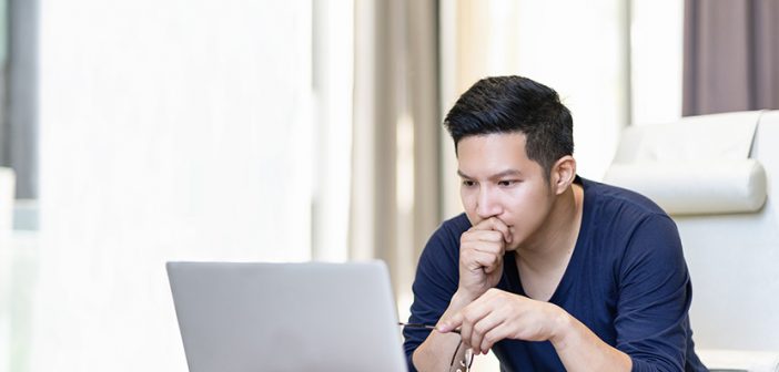 confident asian young freelancer in smart casual working and concentrated on laptop sitting on desk in modern office ,co-working space or at home with copy space, webinar over the internet