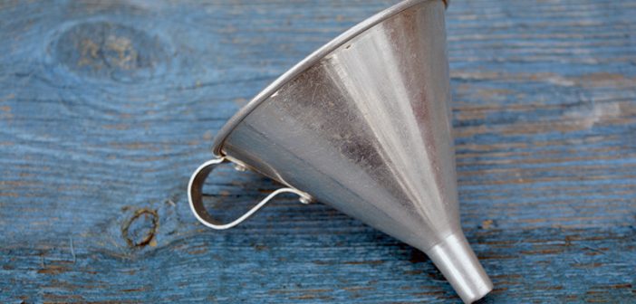 Vintage metal funnel with handle on old wooden garden table background